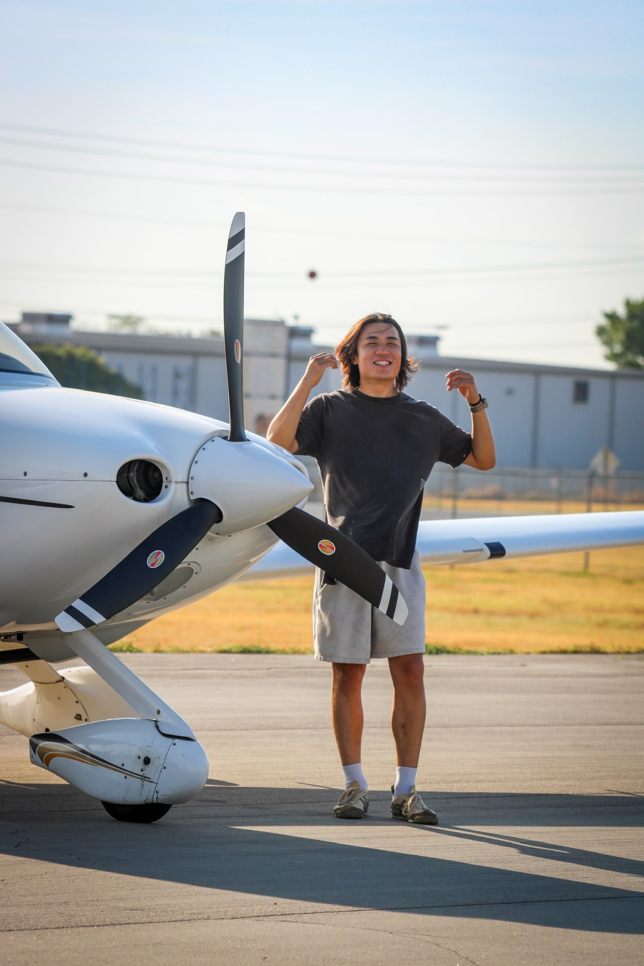 A person smiling beside a Cirrus outside the hangar
