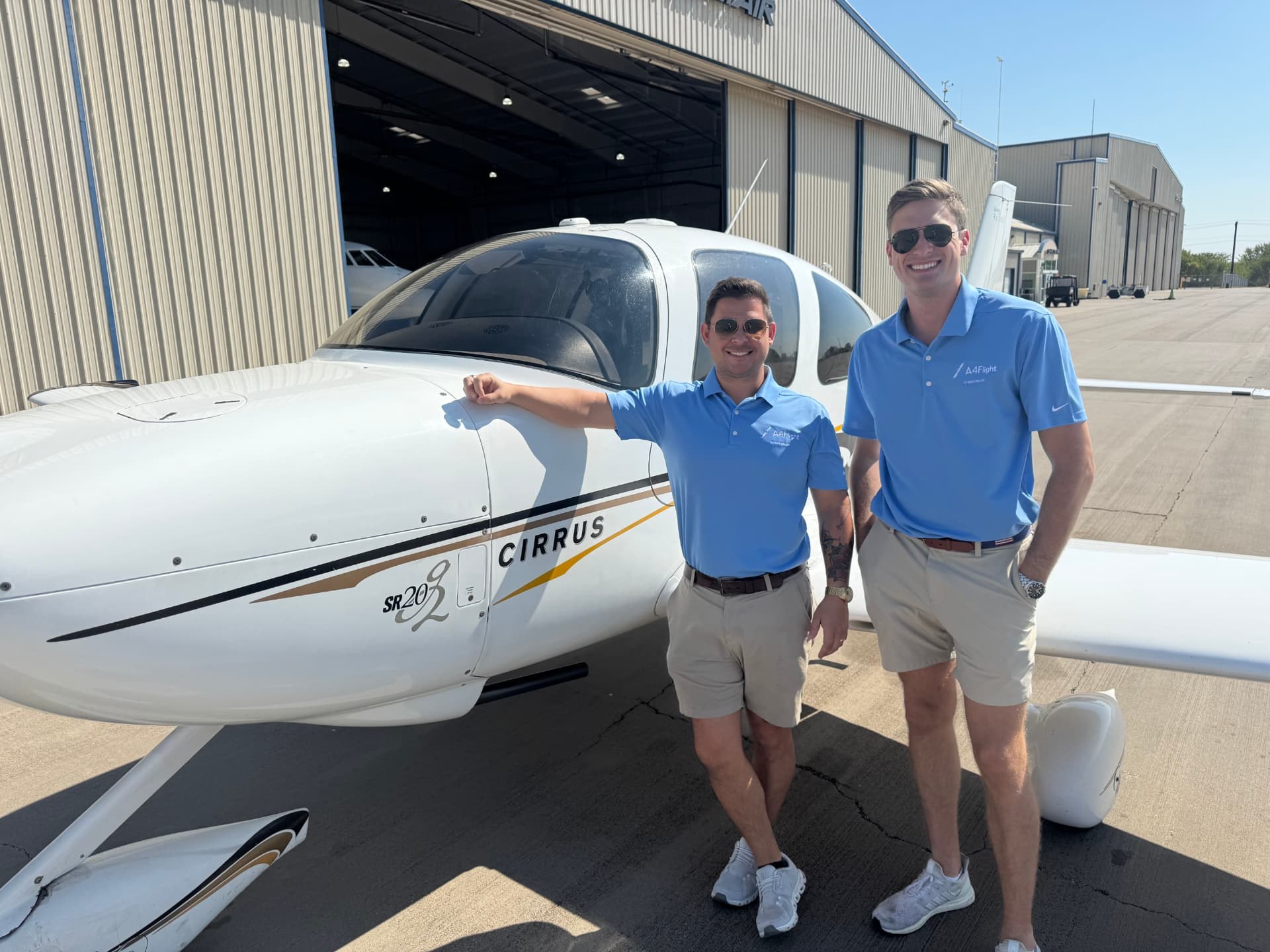 Two people beside an A4Flight Cirrus at the Denton hangar