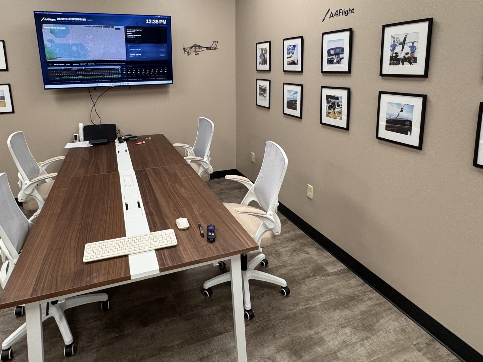 The A4Flight briefing room at Sheltair: conference table, wall-mounted flight board, A4Flight lettering and a wall gallery of club photos.