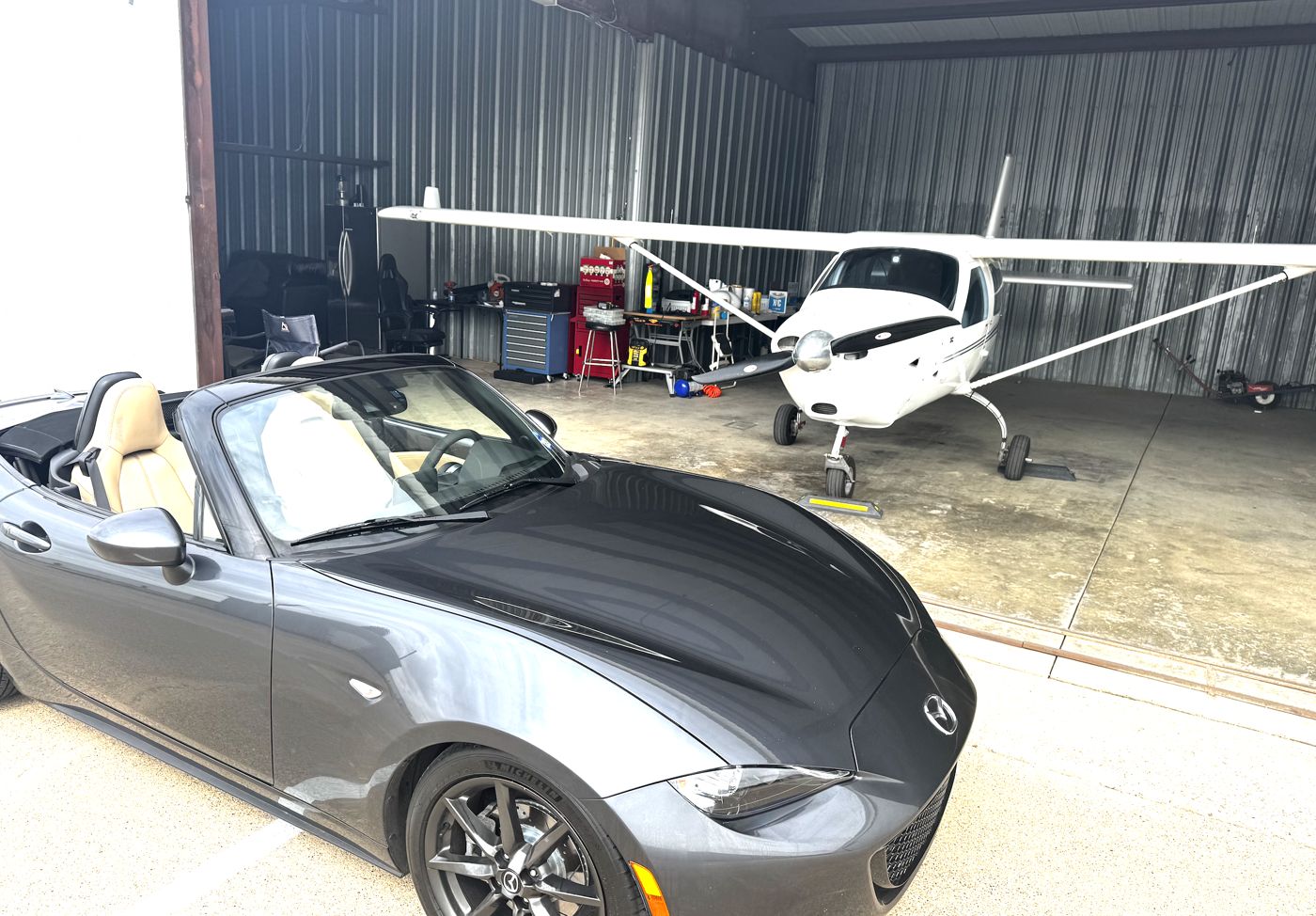 Jabiru J170 parked in the hangar behind a gray convertible sports car