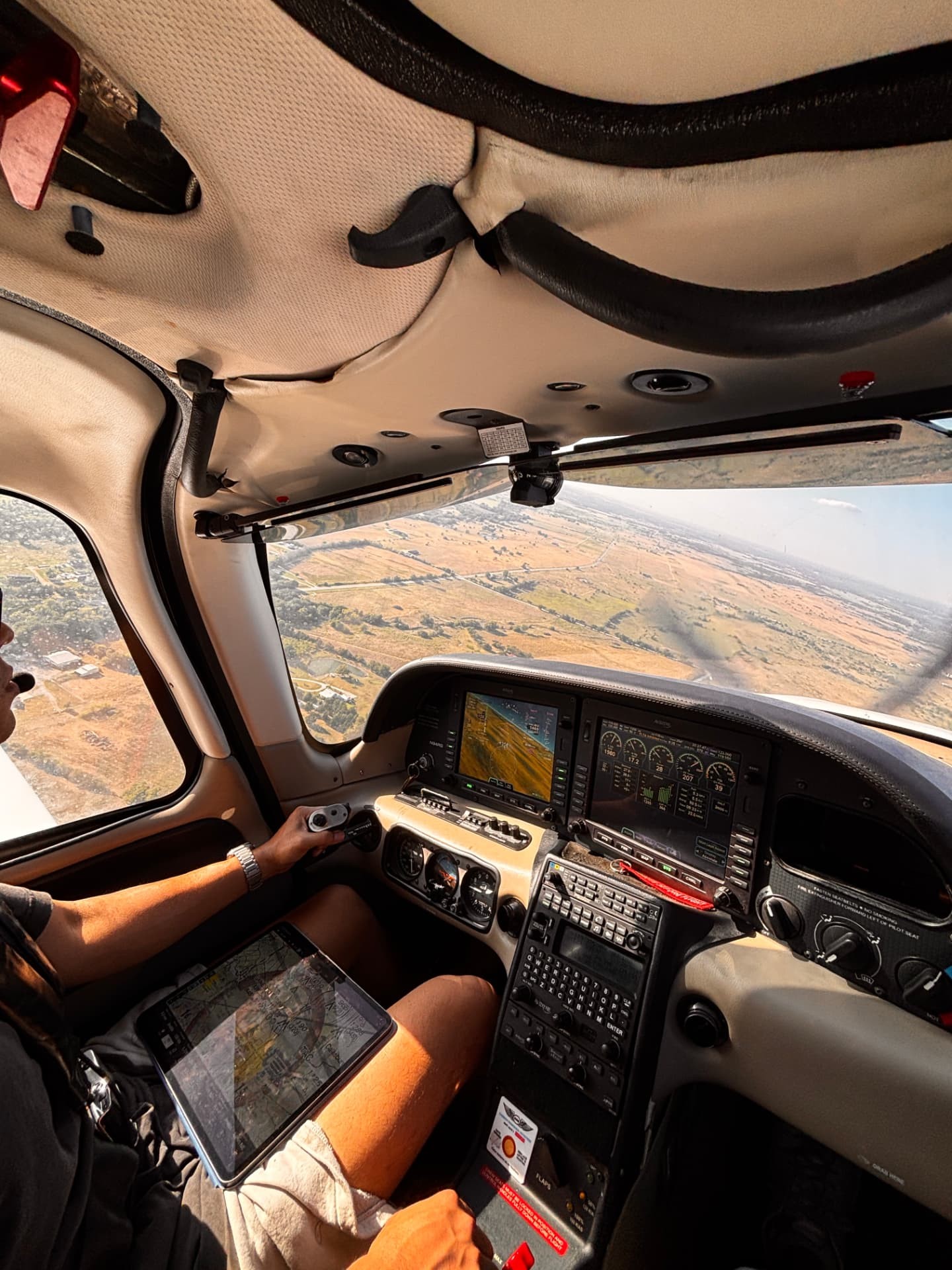 Pilot at the controls of a Cirrus with the glass cockpit and landscape in view