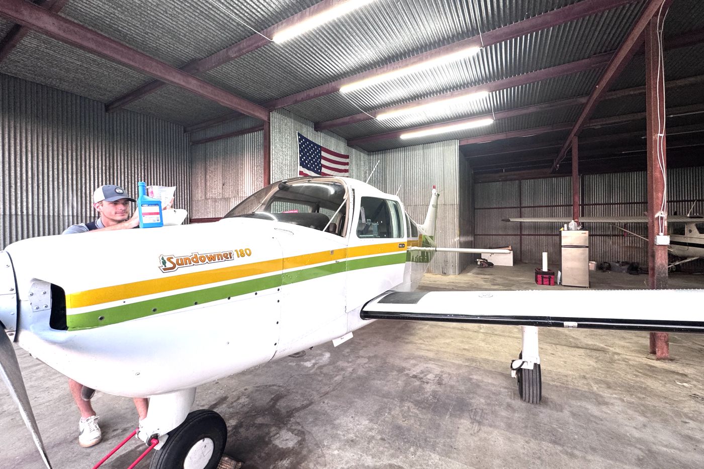 Older Piper airplane parked inside a hangar