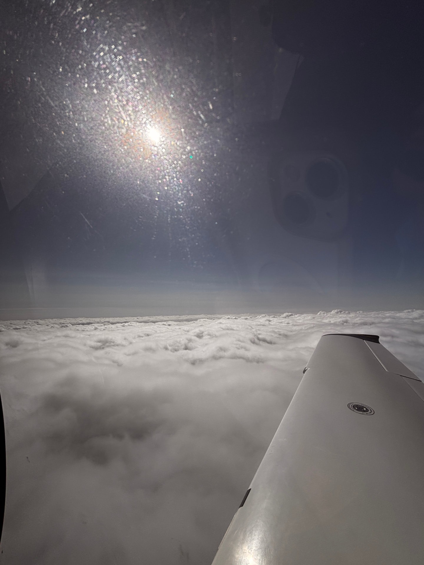 Cirrus wing above a layer of clouds, photographed through the cabin window