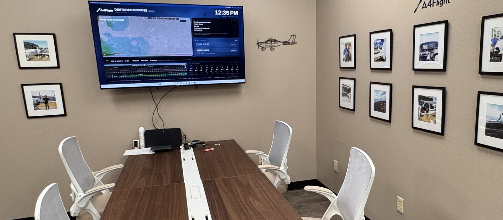 Wide view of the A4Flight briefing room, looking along the conference table to the flight board and the club photo gallery.