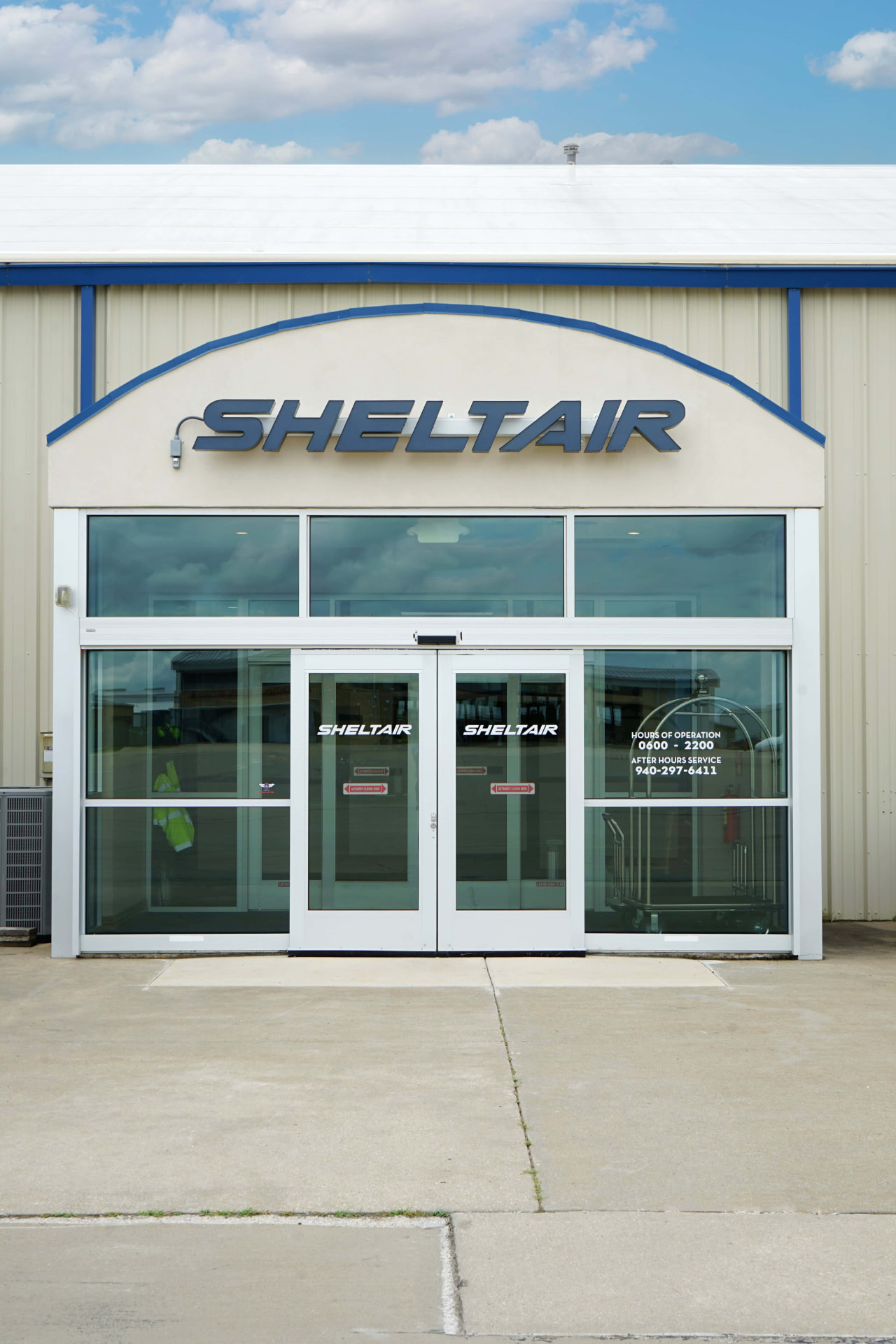 Sheltair terminal entrance at Denton Enterprise Airport with posted hours of operation